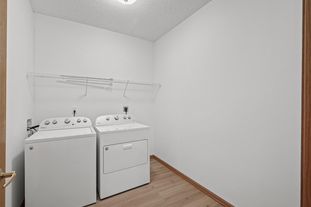 washroom featuring washing machine and dryer, light wood-type flooring, and a textured ceiling