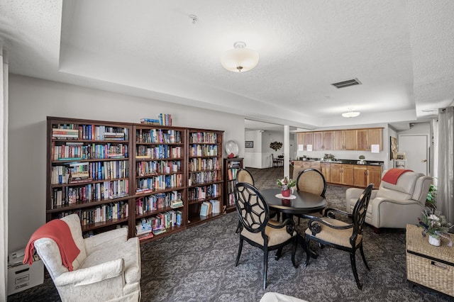 dining space featuring a raised ceiling, a textured ceiling, and dark colored carpet