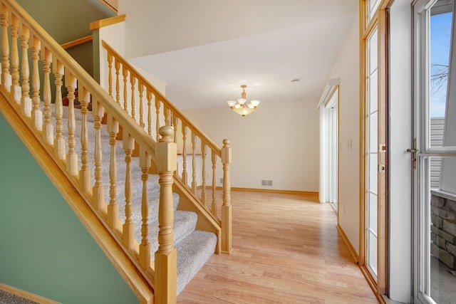 entrance foyer featuring visible vents, baseboards, an inviting chandelier, light wood-style floors, and stairway