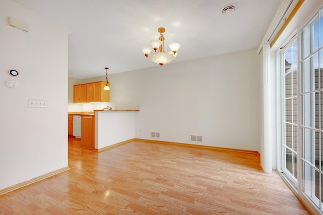 interior space featuring light wood-style floors, visible vents, baseboards, and an inviting chandelier