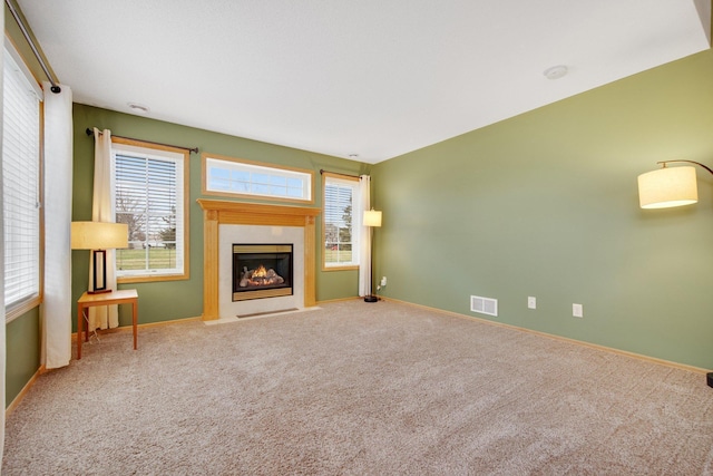 unfurnished living room with visible vents, baseboards, a fireplace with flush hearth, and carpet floors