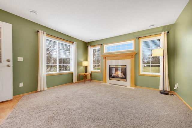 unfurnished living room with a fireplace with flush hearth, baseboards, and carpet