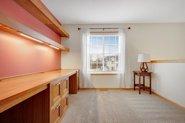 office area featuring baseboards and light carpet