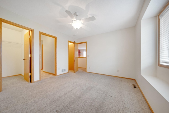 unfurnished bedroom with visible vents, a spacious closet, multiple windows, and light colored carpet
