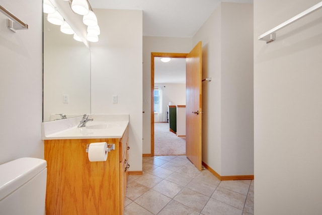 bathroom with tile patterned flooring, vanity, baseboards, and toilet