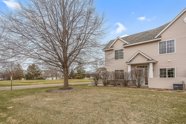 view of front of home with central AC, a front lawn, and a shingled roof