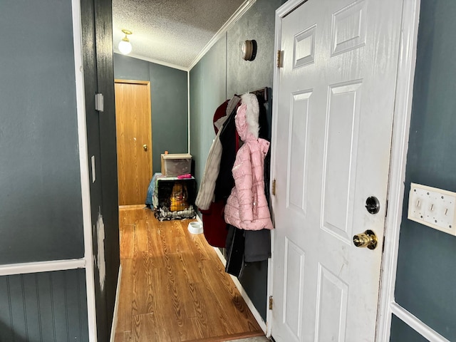 doorway featuring hardwood / wood-style floors, a textured ceiling, lofted ceiling, and ornamental molding