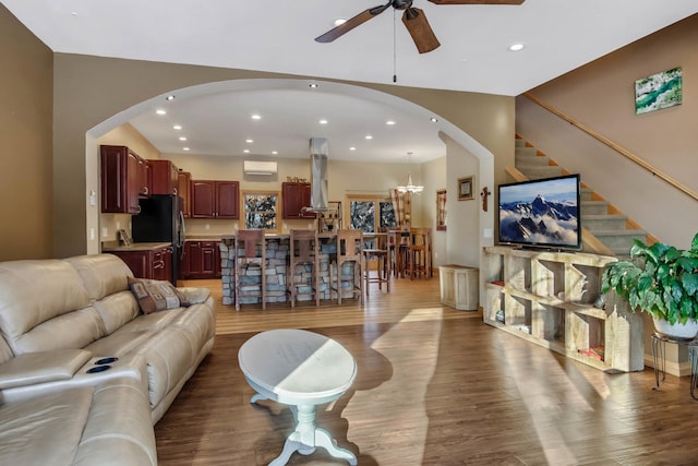 living area with ceiling fan with notable chandelier, recessed lighting, stairway, and wood finished floors