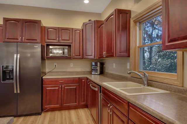 kitchen featuring light wood-style flooring, stainless steel appliances, light countertops, a sink, and recessed lighting