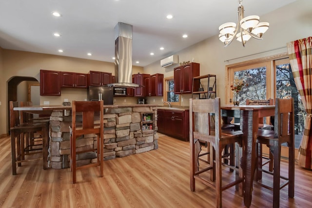 kitchen featuring arched walkways, pendant lighting, stainless steel appliances, light countertops, and a wall mounted air conditioner