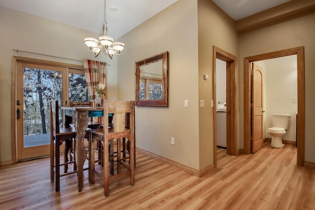 dining area with light wood-type flooring, baseboards, a chandelier, and vaulted ceiling