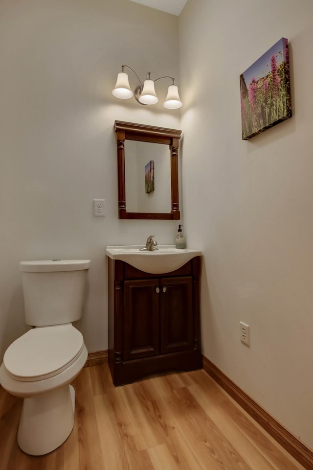 bathroom with baseboards, wood finished floors, toilet, and vanity