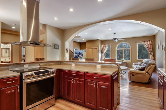 N1865 980th St, Rock Creek Twp, WI 54701 - kitchen featuring stainless steel electric range, island exhaust hood, reddish brown cabinets, open floor plan, and arched walkways