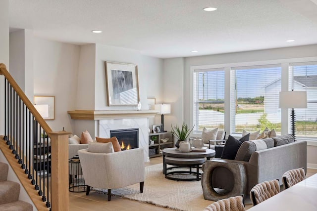 living room with a high end fireplace and light wood-type flooring