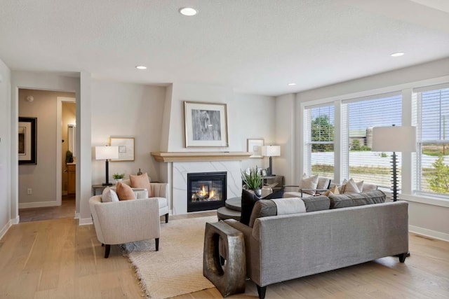 living room featuring plenty of natural light, light wood-type flooring, and a tile fireplace