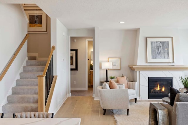 living room with a premium fireplace, a textured ceiling, and light hardwood / wood-style flooring