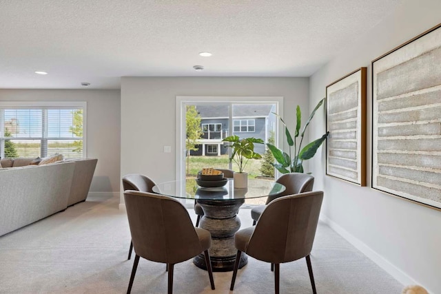 dining space with light colored carpet and a textured ceiling