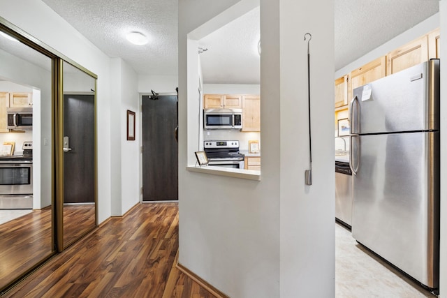 kitchen featuring dark hardwood / wood-style flooring, light brown cabinets, a textured ceiling, and appliances with stainless steel finishes