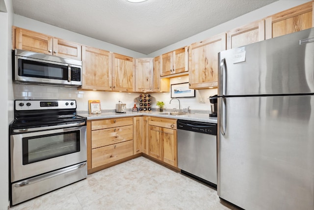 kitchen featuring sink, stainless steel appliances, a textured ceiling, decorative backsplash, and light brown cabinetry