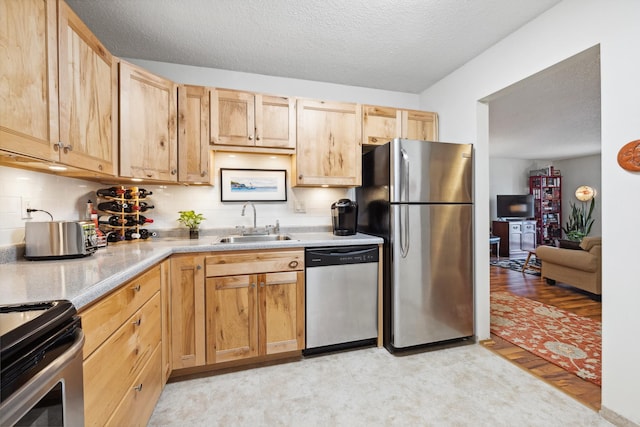 kitchen featuring tasteful backsplash, light brown cabinetry, sink, and appliances with stainless steel finishes