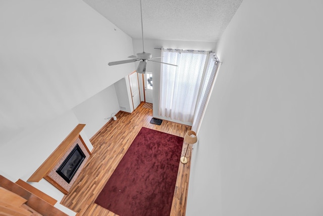 living room with a textured ceiling, ceiling fan, and light hardwood / wood-style floors