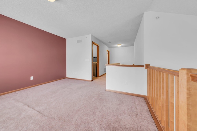 carpeted empty room featuring a textured ceiling