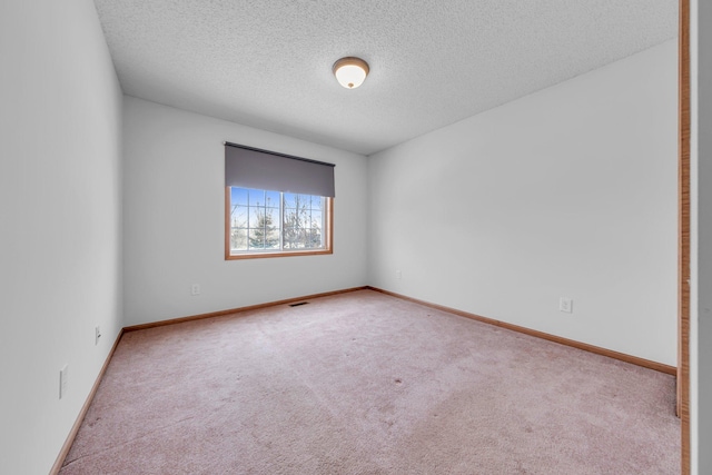 unfurnished room featuring a textured ceiling and light carpet