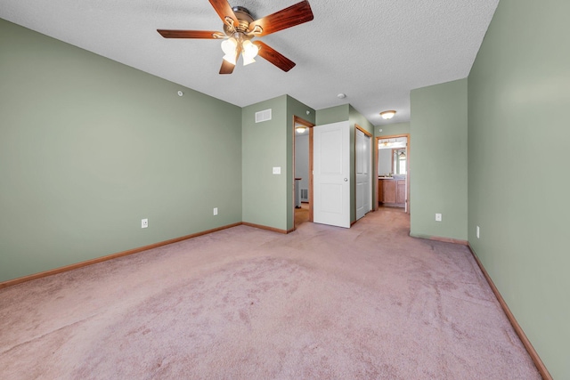 unfurnished bedroom featuring ensuite bathroom, a textured ceiling, ceiling fan, and light colored carpet