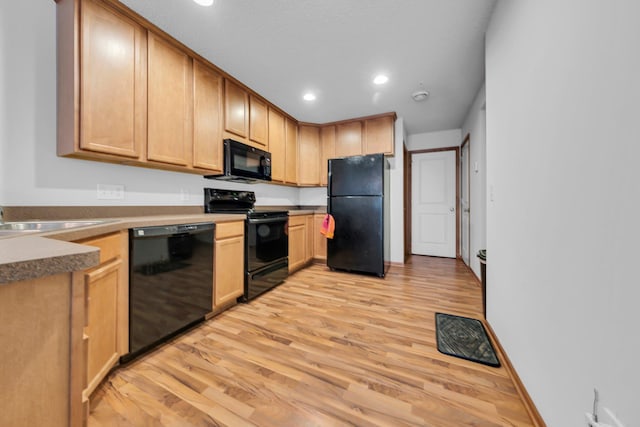 kitchen featuring light brown cabinetry, sink, light wood-type flooring, and black appliances