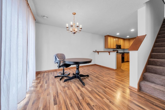 dining area featuring a textured ceiling, a chandelier, and light hardwood / wood-style flooring