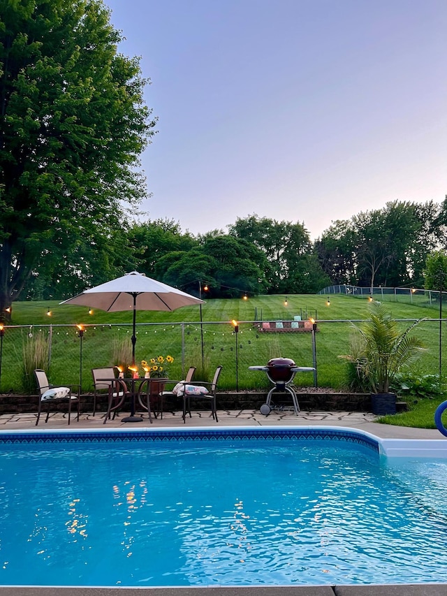 view of pool with a patio and a lawn