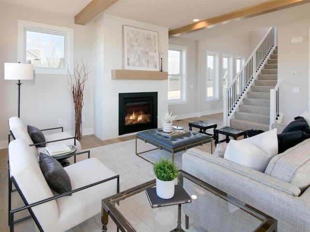 living area featuring beamed ceiling, plenty of natural light, and wood finished floors