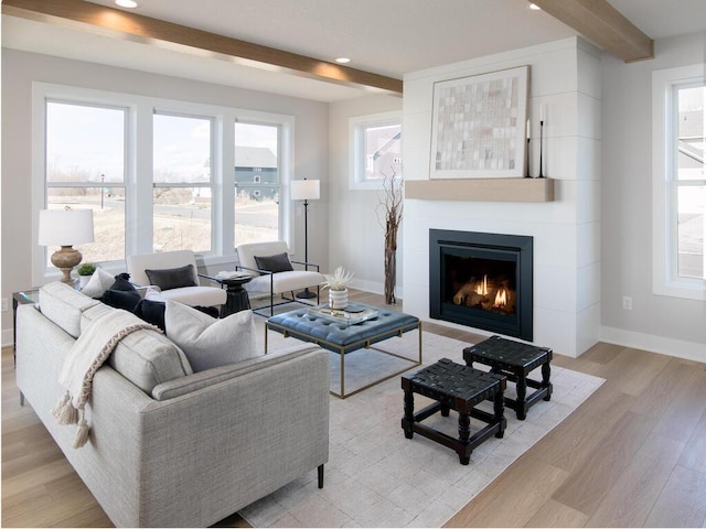 living room with beamed ceiling, recessed lighting, light wood-style floors, a lit fireplace, and baseboards