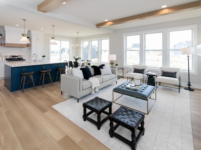 living area featuring beamed ceiling, plenty of natural light, and baseboards