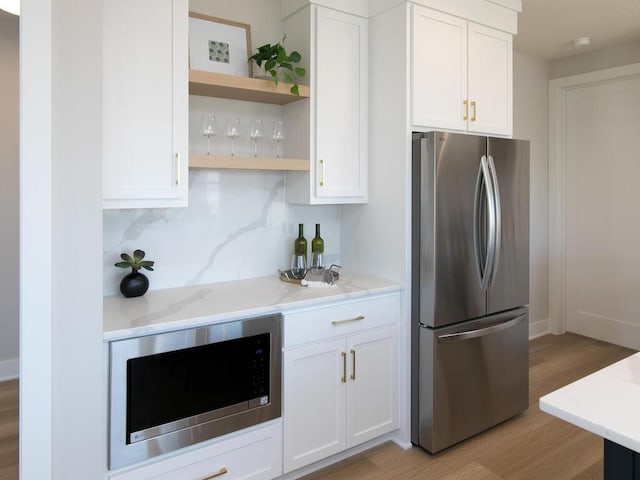 kitchen featuring open shelves, white cabinets, light stone counters, and stainless steel appliances