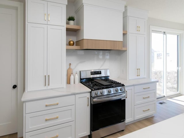 kitchen with visible vents, open shelves, white cabinetry, gas range, and light wood-type flooring