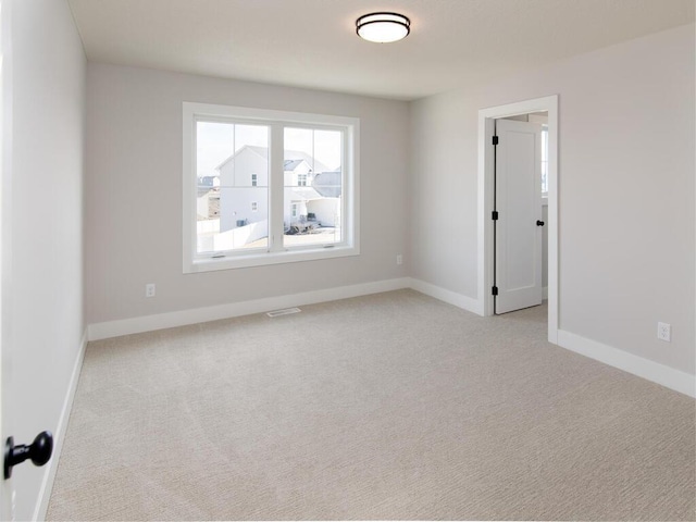 spare room with visible vents, light colored carpet, and baseboards