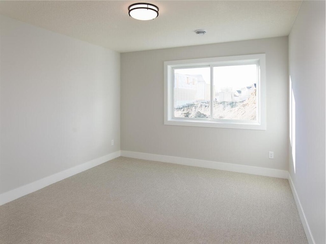 empty room featuring light colored carpet and baseboards