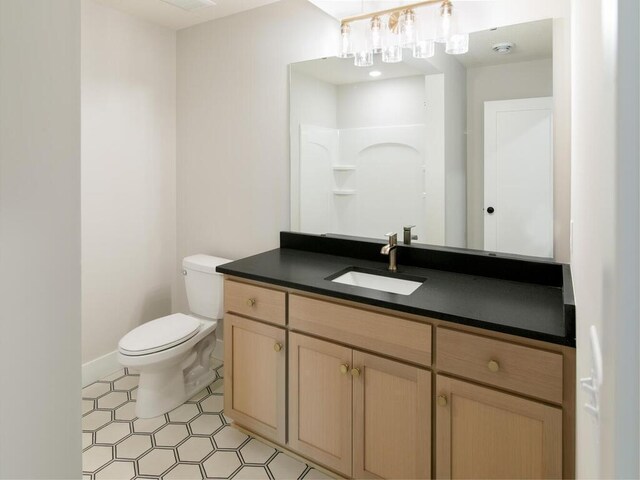 bathroom with baseboards, toilet, vanity, and walk in shower