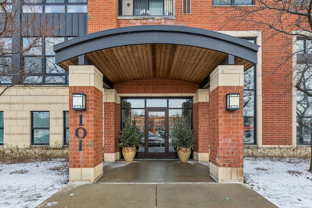 snow covered property entrance featuring french doors