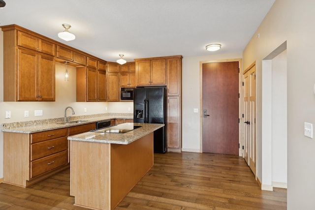 kitchen with black appliances, a kitchen island, dark hardwood / wood-style flooring, sink, and light stone counters