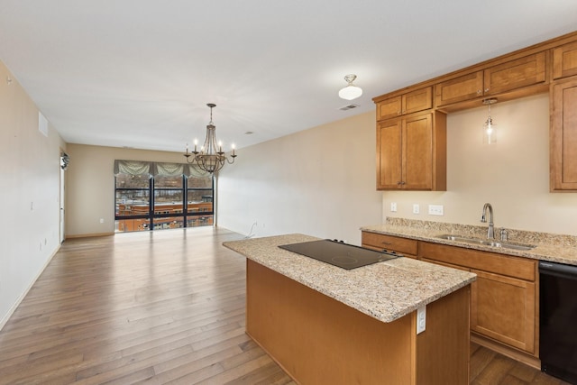 kitchen with a center island, black appliances, sink, an inviting chandelier, and hanging light fixtures