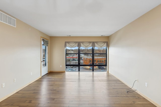 spare room with visible vents, baseboards, and wood finished floors