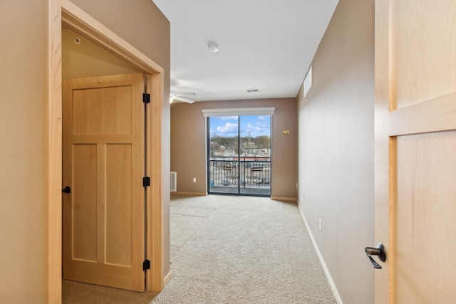 hall with light carpet, visible vents, and baseboards