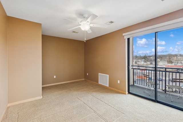 empty room with carpet floors, baseboards, visible vents, and a ceiling fan