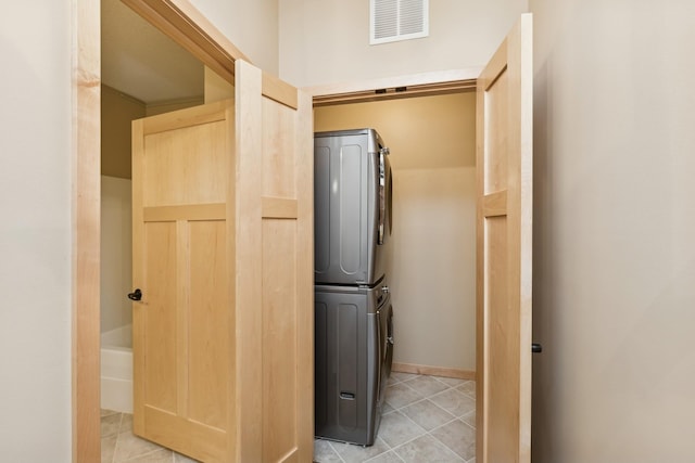 laundry room featuring stacked washer / drying machine, laundry area, visible vents, and light tile patterned floors