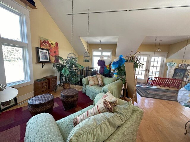 living room with hardwood / wood-style flooring, high vaulted ceiling, french doors, and a healthy amount of sunlight