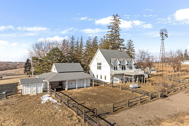 rear view of house featuring a shed and a rural view