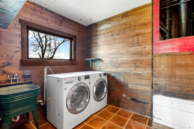 clothes washing area featuring tile patterned flooring, washer and clothes dryer, and wooden walls