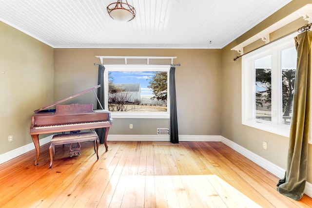 misc room featuring wood-type flooring, ornamental molding, and plenty of natural light